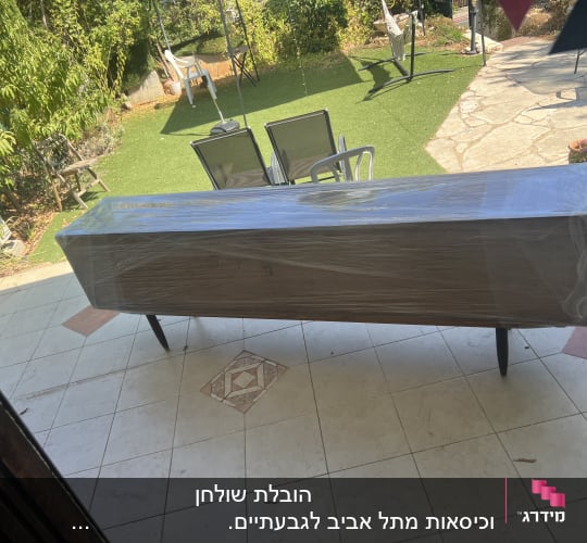 רהיט עטוף בניילון בגינה עם דשא וכיסאות